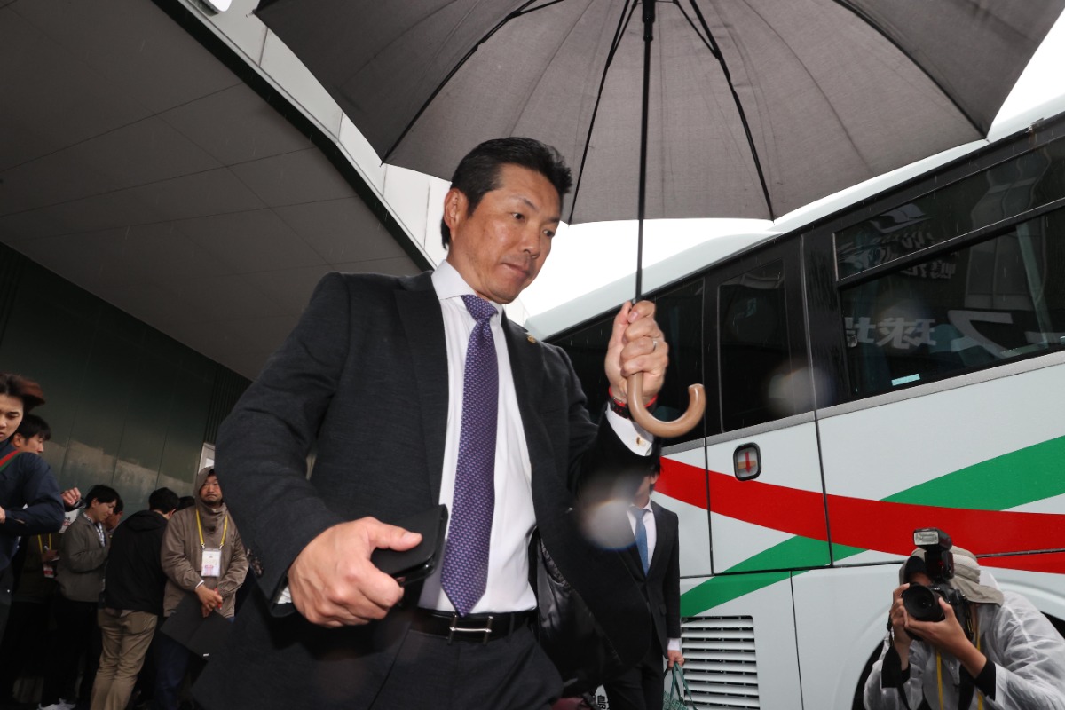 傘をさして球場を後にする小久保裕紀監督【写真：栗木一考】