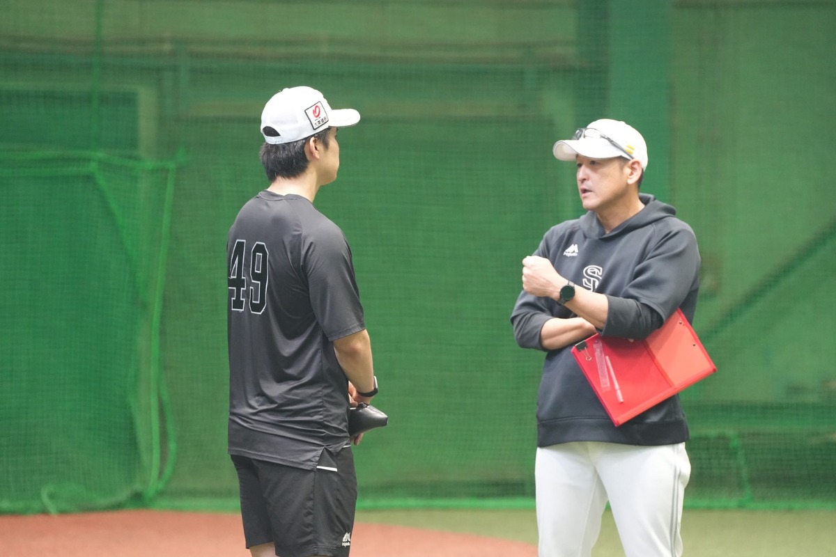 松本晴と言葉を交わす倉野信次投手コーチ（右）【写真：森大樹】